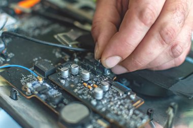 Bir adam bilgisayarı tamir eder, lehimler, elektronik ve modern teknolojileri tamir eder.