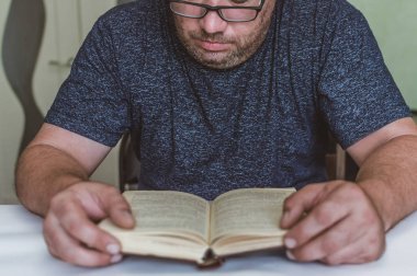 adam masada bir kitap okuma, okurken bir aperatif sahip, kısa bir mola