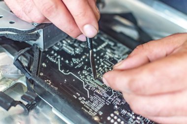 Bir adam bilgisayarı tamir eder, lehimler, elektronik ve modern teknolojileri tamir eder.