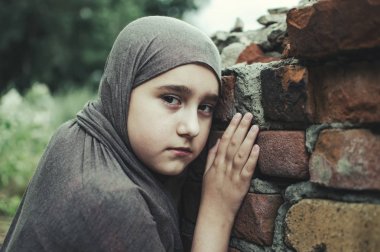 savaşta bir mülteci çocuk, harabeler üzerinde kirli bir yüzü olan Müslüman bir kız, barış ve savaş kavramı, çocuk ağlıyor ve yardım bekliyor.