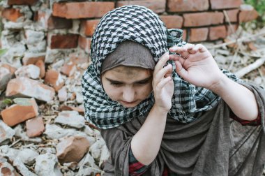 savaşta bir mülteci çocuk, harabeler üzerinde kirli bir yüzü olan Müslüman bir kız, barış ve savaş kavramı, çocuk ağlıyor ve yardım bekliyor.