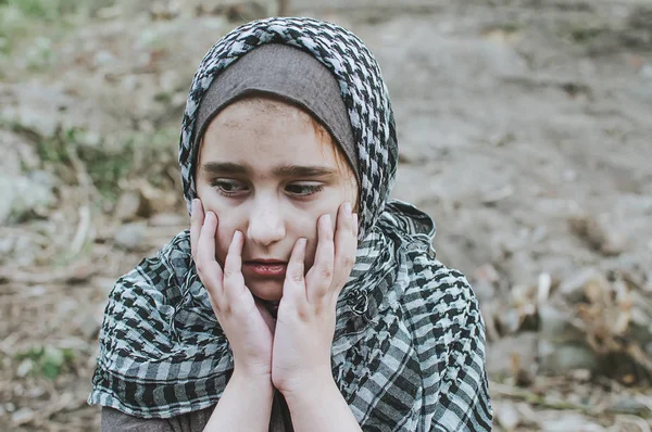 Un niño refugiado en la guerra, una niña musulmana con una cara sucia en las ruinas, el concepto de paz y guerra, el niño está llorando y esperando ayuda . — Foto de Stock