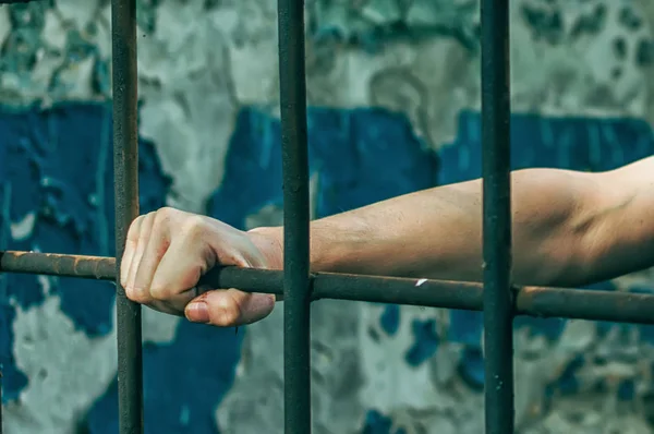 Депресивний чоловік у наручниках за ґратами. Затриманого чоловіка-втікача у в'язниці затримано. Крики, перерви, крики . — стокове фото
