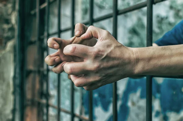 Parmaklıklar ardında elleri kelepçeli depresif bir adam. Depresyonda olan bir erkek suçlu hapse atıldı. Haykırıyor, kırıyor, ağlıyor. — Stok fotoğraf