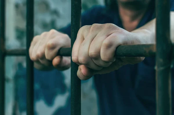 Un hombre deprimido esposado tras las rejas. Un delincuente detenido deprimido es encarcelado. Gritos, descansos, gritos . —  Fotos de Stock