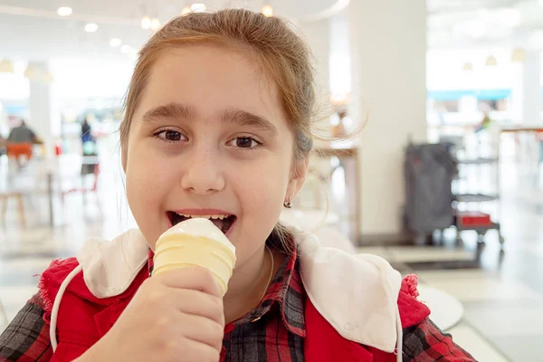Teenage girl eating ice cream in a cone at a food court mall. Unhealthy food. — Stock Photo, Image