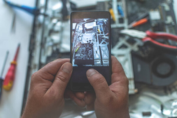 a man repairs a computer, solders a board, repairs electronics a