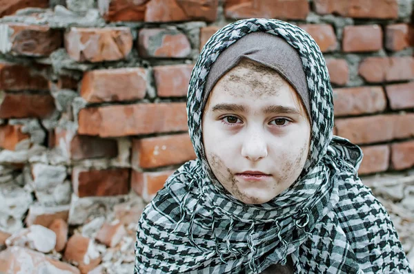 Un niño refugiado en la guerra, una niña musulmana con una cara sucia en las ruinas, el concepto de paz y guerra, el niño está llorando y esperando ayuda . — Foto de Stock