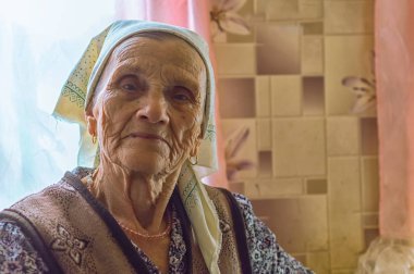 bir huzurevinde başörtüsü ile yaşlı bir bekar kadının yüzü kameraya bakarak