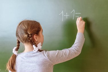 Schoolgirl ders sırasında kara tahta üzerinde bir matematik sorunu çözer.