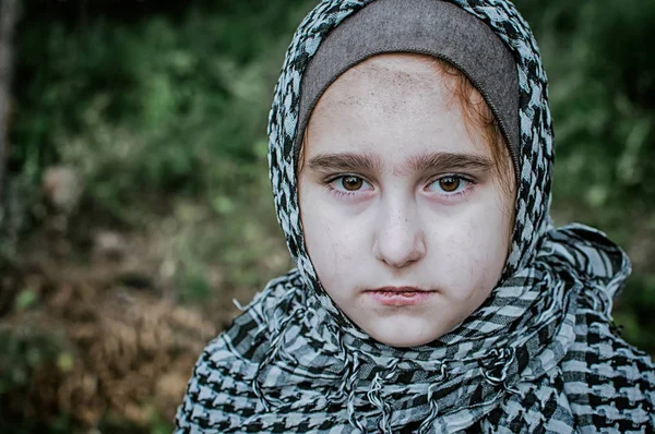 A refugee child in the war, a Muslim girl with a dirty face on the ruins, the concept of peace and war, the child is crying and waiting for help. — Stock Photo, Image