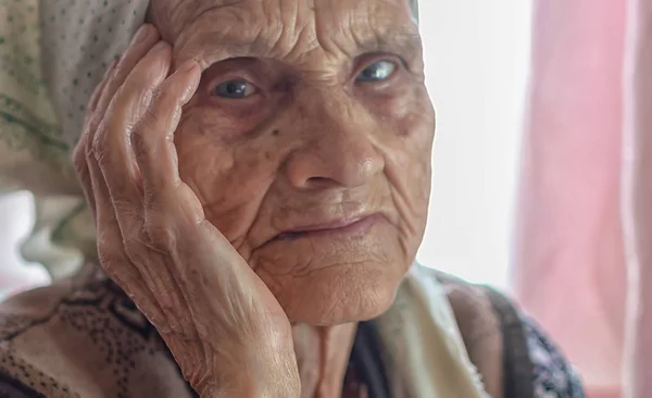 面对一个老单身妇女在养老院的头巾看着相机 — 图库照片