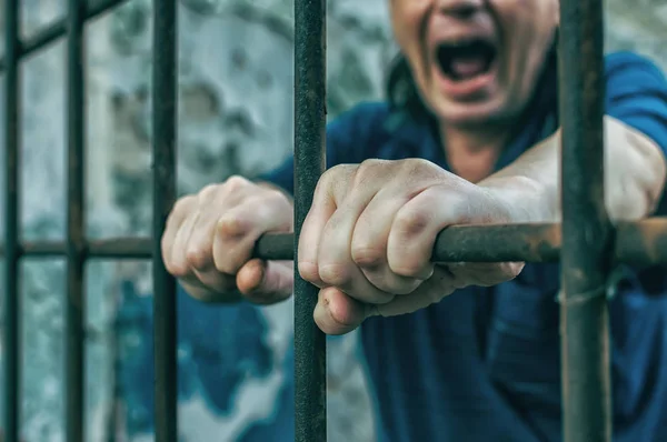 Un hombre deprimido esposado tras las rejas. Un delincuente detenido deprimido es encarcelado. Gritos, descansos, gritos . —  Fotos de Stock