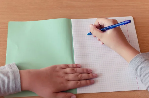 Hand van een tiener meisje schrijft met een balpen in een terad tijdens een les op school — Stockfoto