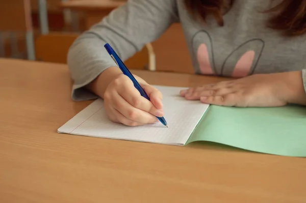 Hand van een tiener meisje schrijft met een balpen in een terad tijdens een les op school — Stockfoto