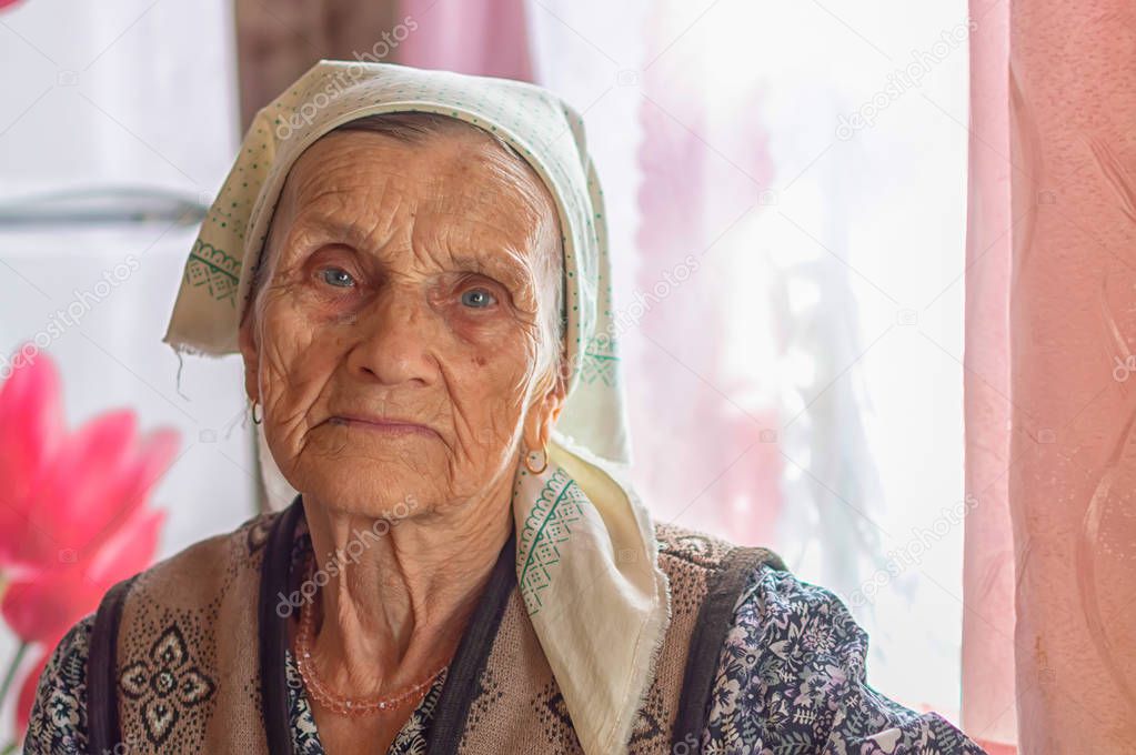 face of an old single woman in a headscarf in a nursing home looking at the camera