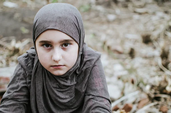 Ve válce uprchlické dítě, muslimská dívka se špinavou tváří na troskách, koncept míru a války, dítě pláče a čeká na pomoc. — Stock fotografie