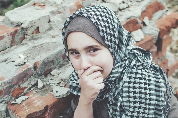 Un enfant réfugié dans la guerre, une fille musulmane avec un visage sale sur les ruines, le concept de paix et de guerre, l'enfant pleure et attend de l'aide . — Photo