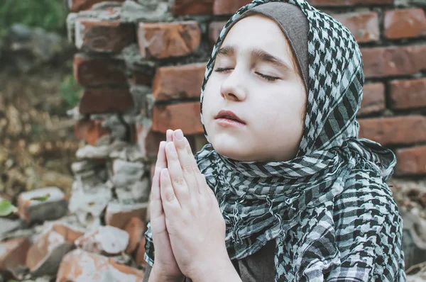 Un niño refugiado en la guerra, una niña musulmana con una cara sucia en las ruinas, el concepto de paz y guerra, el niño está llorando y esperando ayuda . — Foto de Stock