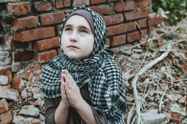 Un niño refugiado en la guerra, una niña musulmana con una cara sucia en las ruinas, el concepto de paz y guerra, el niño está llorando y esperando ayuda . —  Fotos de Stock