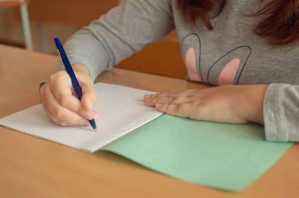 Mano de una adolescente escribe con un bolígrafo en una terad durante una lección en la escuela — Foto de Stock