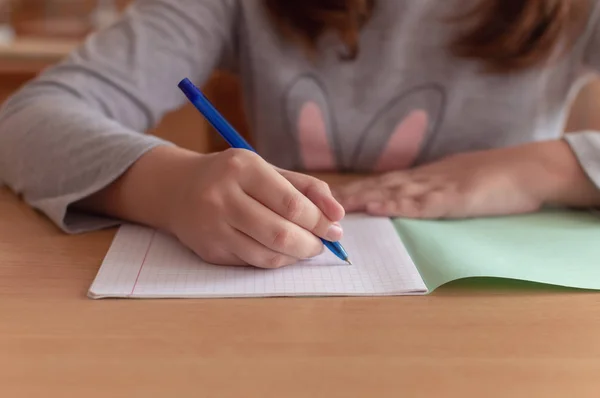 Hand van een tiener meisje schrijft met een balpen in een terad tijdens een les op school — Stockfoto