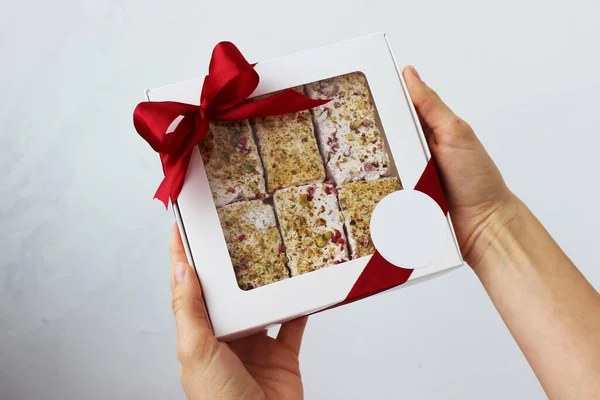 Hands holding a box of homemade nougat. Work at home. Horizontal photo. Selective focus.