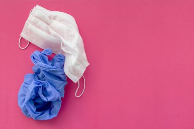 Pembe arka planda kullanıldıktan sonra tıbbi maske ve mavi tıbbi eldiven. Mesaj için yer var. Seçici odaklanma. Kapat..