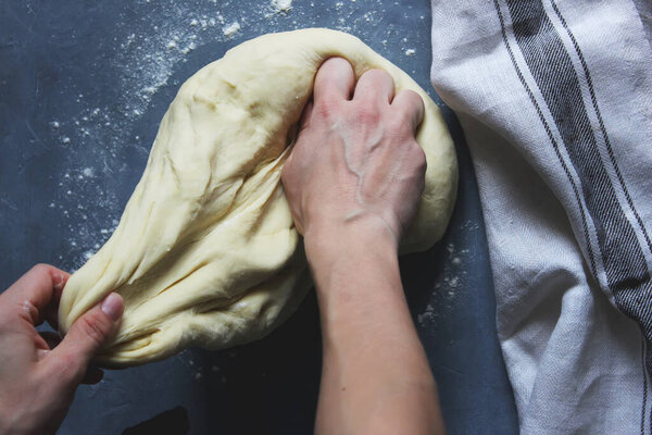 The woman's hands are kneading a tight dough for dumplings on the table. Home cooking. Selective focus. Close up.