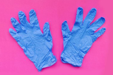 Pembe arka planda iki mavi tıbbi eldiven. Seçici odaklanma. Kapat..