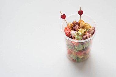 Natürmort renkli patlamış mısır ile Sevgililer günü festival çok renkli patlamış mısır ve beyaz arka plan üzerinde iki kırmızı kalp.