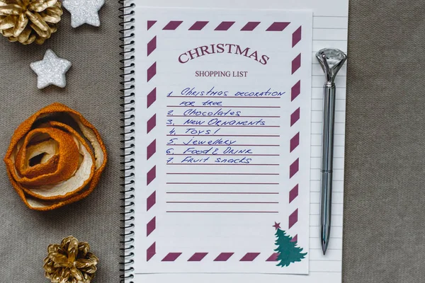 Christmas composition, Christmas shopping list, pen, orange peel, white stars and golden fir cones on a light background, Christmas moods