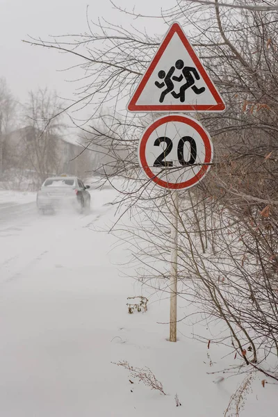 Car on a dangerous winter road, blizzard, speed limit road sign 20 and cautious pedestrians on a white background