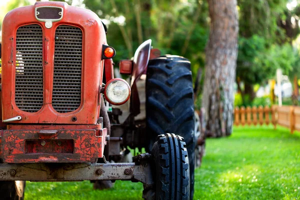 Un viejo tractor rojo cerca de un campo agrícola . —  Fotos de Stock