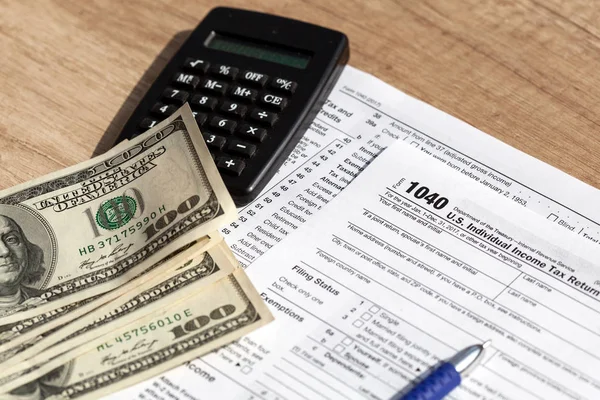 Formulário fiscal 1040 com calculadora e dólares americanos — Fotografia de Stock