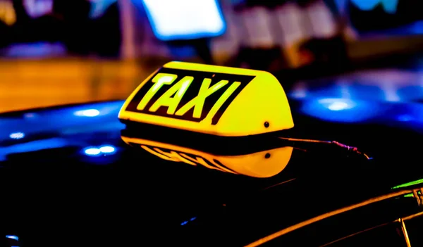 Nachtbild eines Taxiwagens. Taxischild auf dem Autodach leuchtet im Dunkeln — Stockfoto