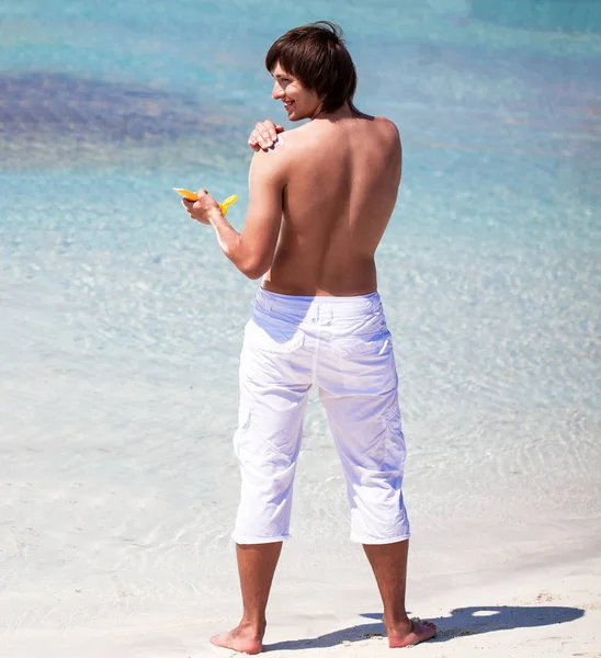 有魅力的年轻人在海滩上擦防晒霜 — 图库照片