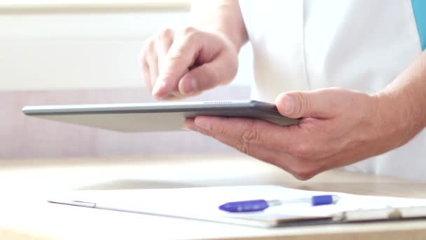 Médico masculino que trabaja con una tableta de pantalla táctil moderna — Vídeos de Stock