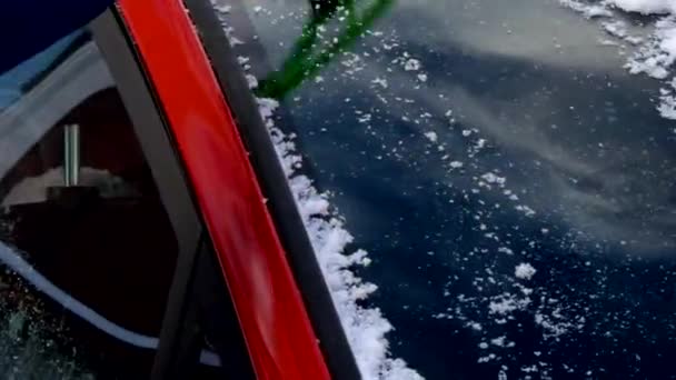 Mujer quitando nieve de la ventana de un coche — Vídeo de stock