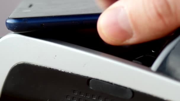 Ein Kunde, der die nfc-Technologie auf seinem Smartphone nutzt, um per PoS-Terminal zu bezahlen. — Stockvideo