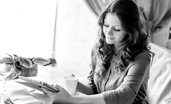 Fiatal nő egy kávézóban kávét iszik. Fekete-fehér fénykép. — Stock Fotó