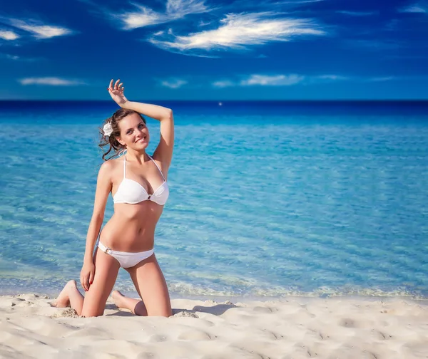 Mujer sensual en bikini blanco sentada en la playa — Foto de Stock
