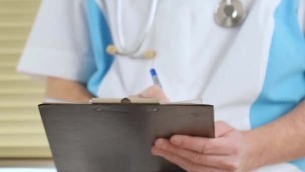 Mannelijke arts arts rx recept schrijven op Klembord voor zijn patiënten — Stockvideo