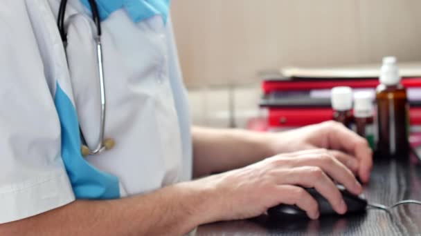 A doctor working on laptop in his cabinet and using computer mouse — Stock Video