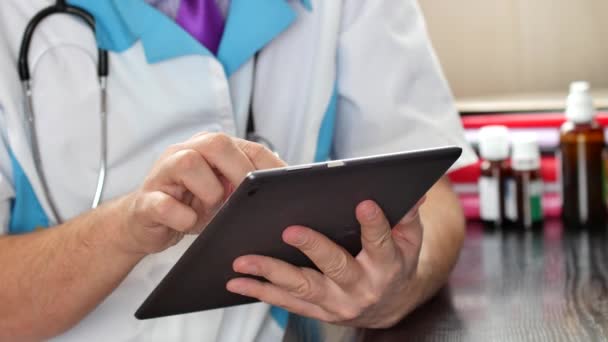 Médico masculino que trabaja con una tableta de pantalla táctil moderna — Vídeos de Stock