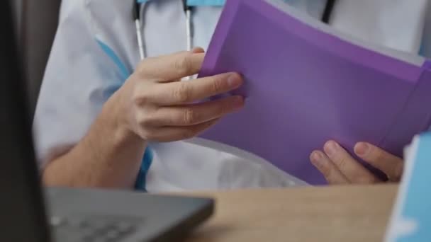 Man läkare arbetar bakom laptop och läsa dokument i skåp — Stockvideo