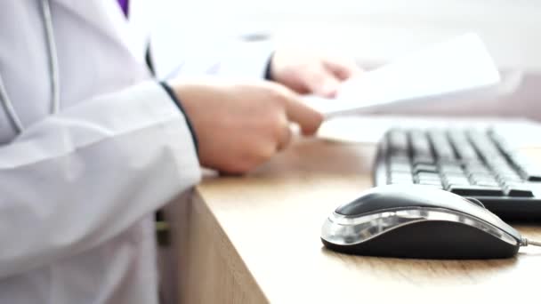 Lékař pracuje na notebooku v jeho kabinetu a klikacích počítačová myš — Stock video