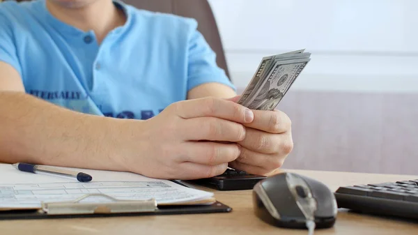 Uomo Maglietta Blu Che Conta Dollari Compila Modulo Delle Tasse — Foto Stock