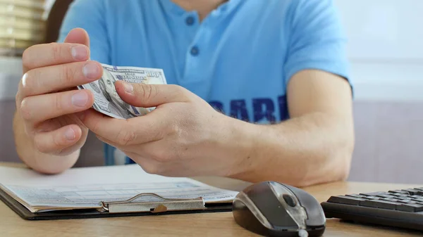 Człowiek Niebieski Shirt Liczenia Dolarów Wypełnienie Formularza Podatkowego Obliczania Kosztów — Zdjęcie stockowe