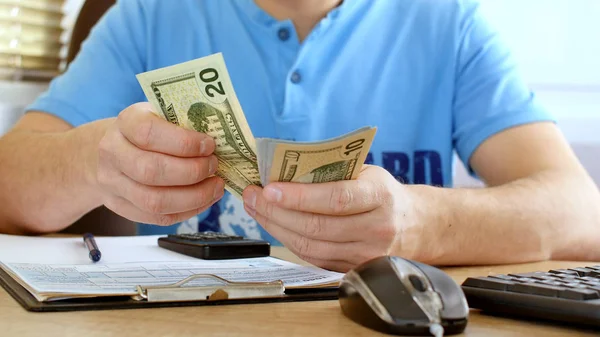 Człowiek Niebieski Shirt Liczenia Dolarów Wypełnienie Formularza Podatkowego Obliczania Kosztów — Zdjęcie stockowe